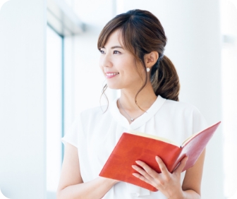窓際で笑顔で佇む女性の画像